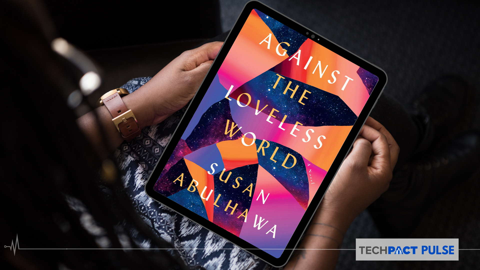 Hands holding a tablet with the front page of Against The Loveless World by Susan Abulhawa on the screen