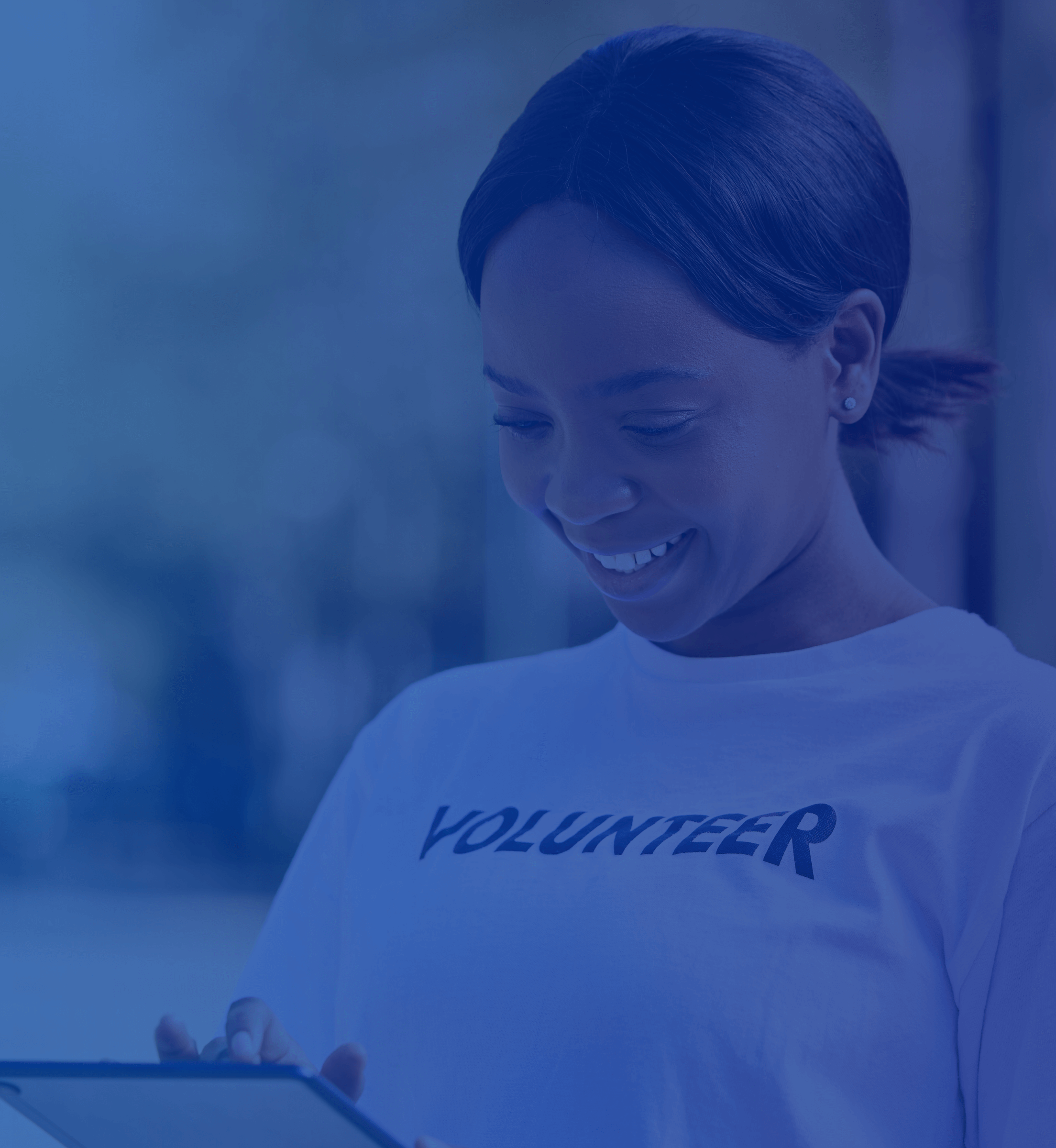A woman who is outdoor wearing a Volunteer shirt working on a tablet while smiling